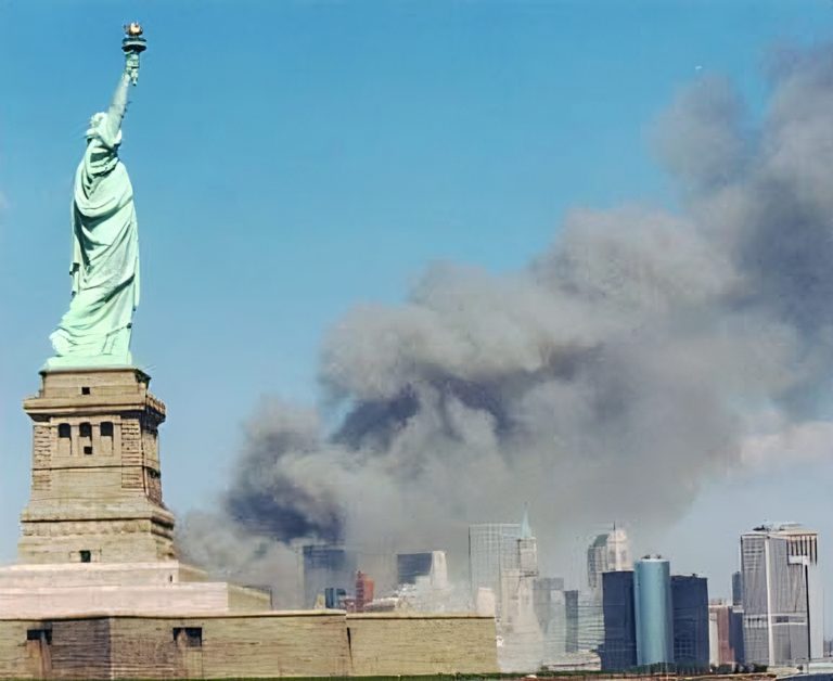 The Statue of Liberty with smoke rising from the World Trade Center towers in the background on September 11, 2001. Photo by U.S. National Park Service, public domain.