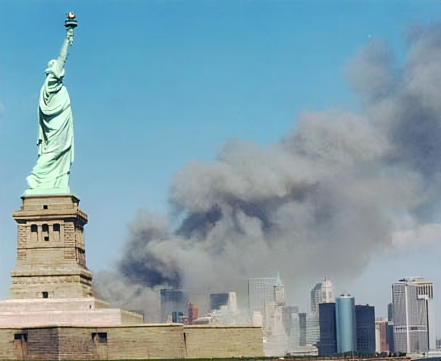 The Statue of Liberty with smoke rising from the World Trade Center towers in the background on September 11, 2001. Photo by U.S. National Park Service, public domain.